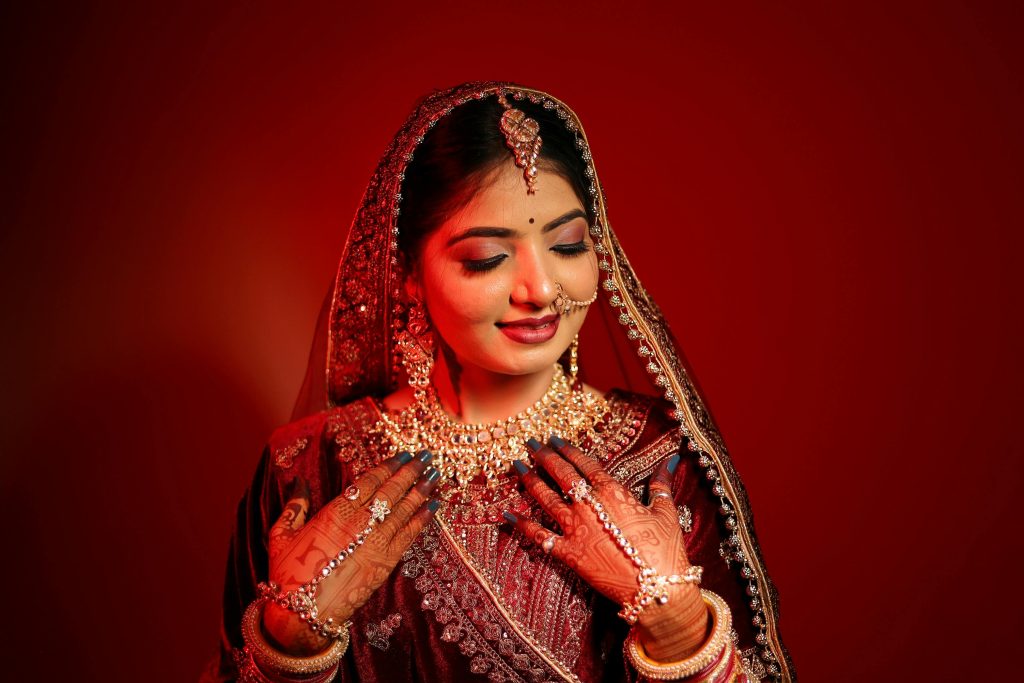 Bridal Makeup Salon in Brampton – Elevate Your Wedding Look with Preeti Design Studio Stunning Indian bride in vibrant traditional bridal wear with intricate jewelry and henna.